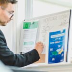 Real estate agent analyzing mortgage loan details on a whiteboard in an office setting.